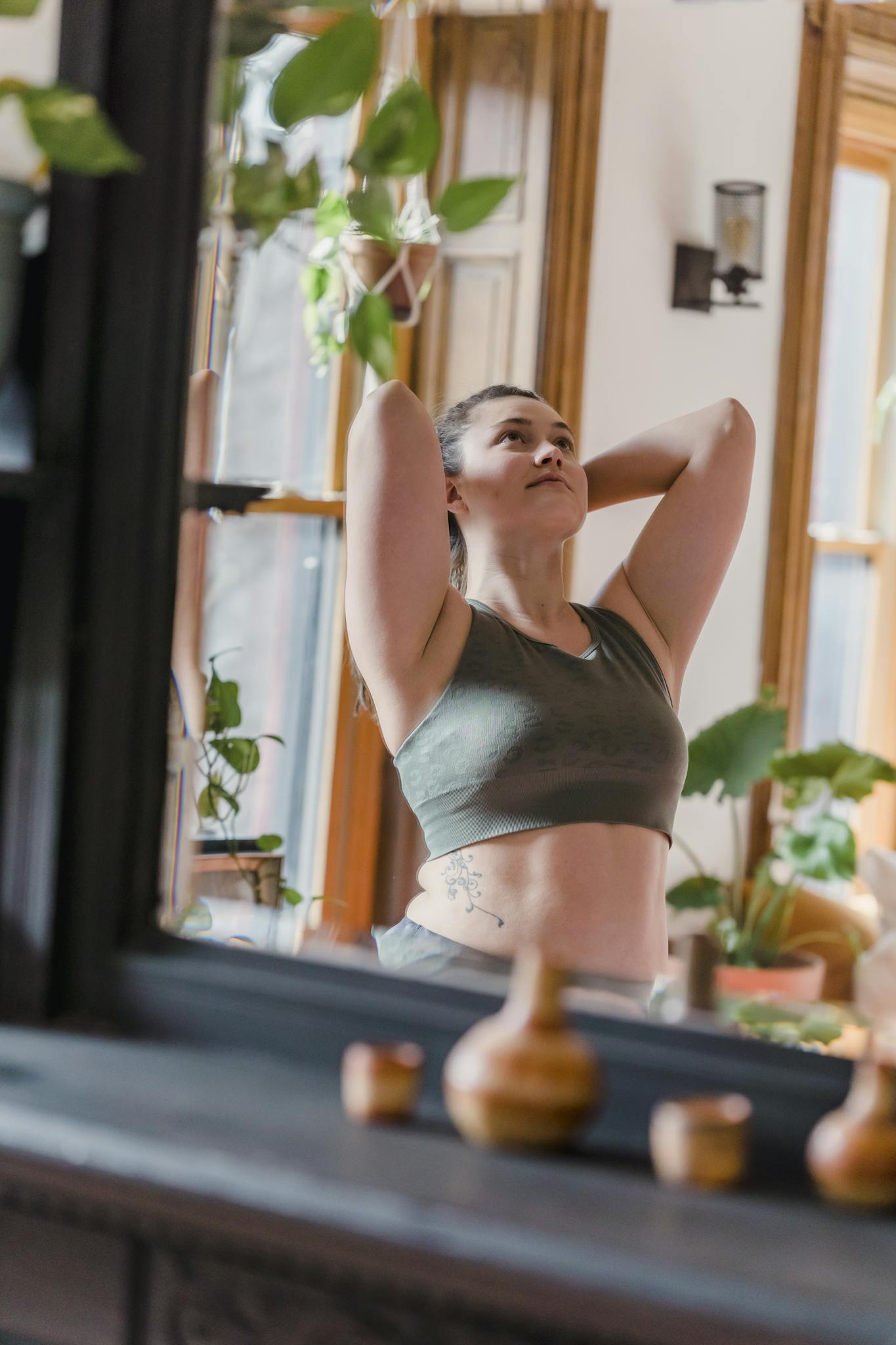Woman doing yoga in a bright room with plants, promoting relaxation and wellness.